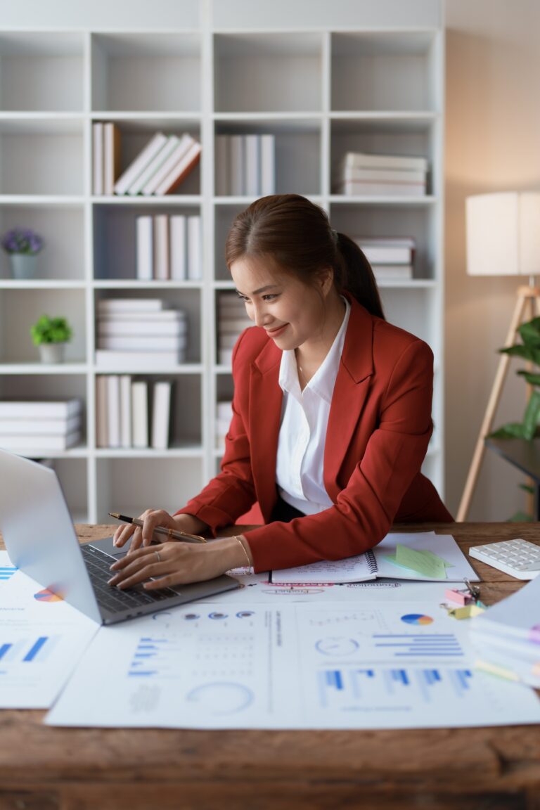 woman meticulously plans a finance audit, using a computer and calculator to review budget documents